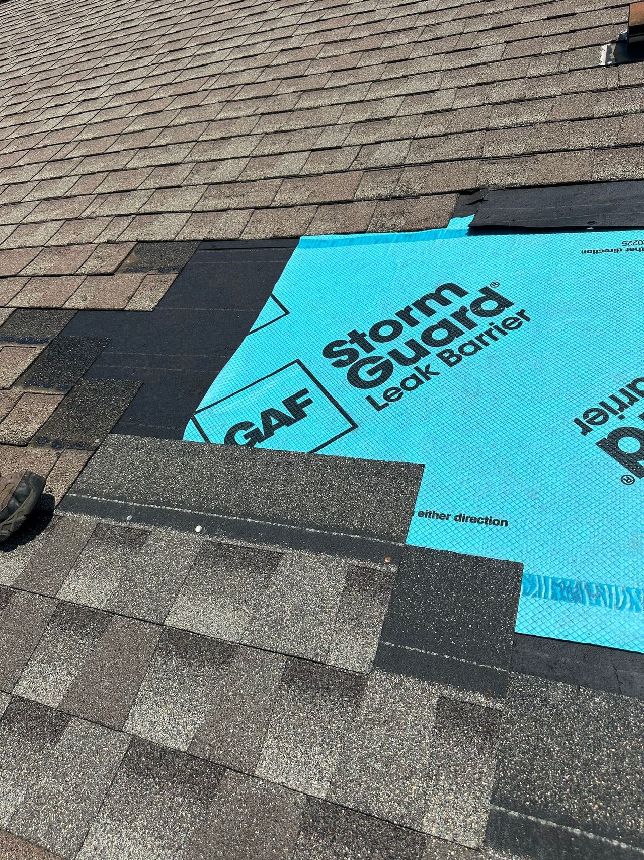 Close-up of a shingle repair showing the GAF StormGuard leak barrier underneath